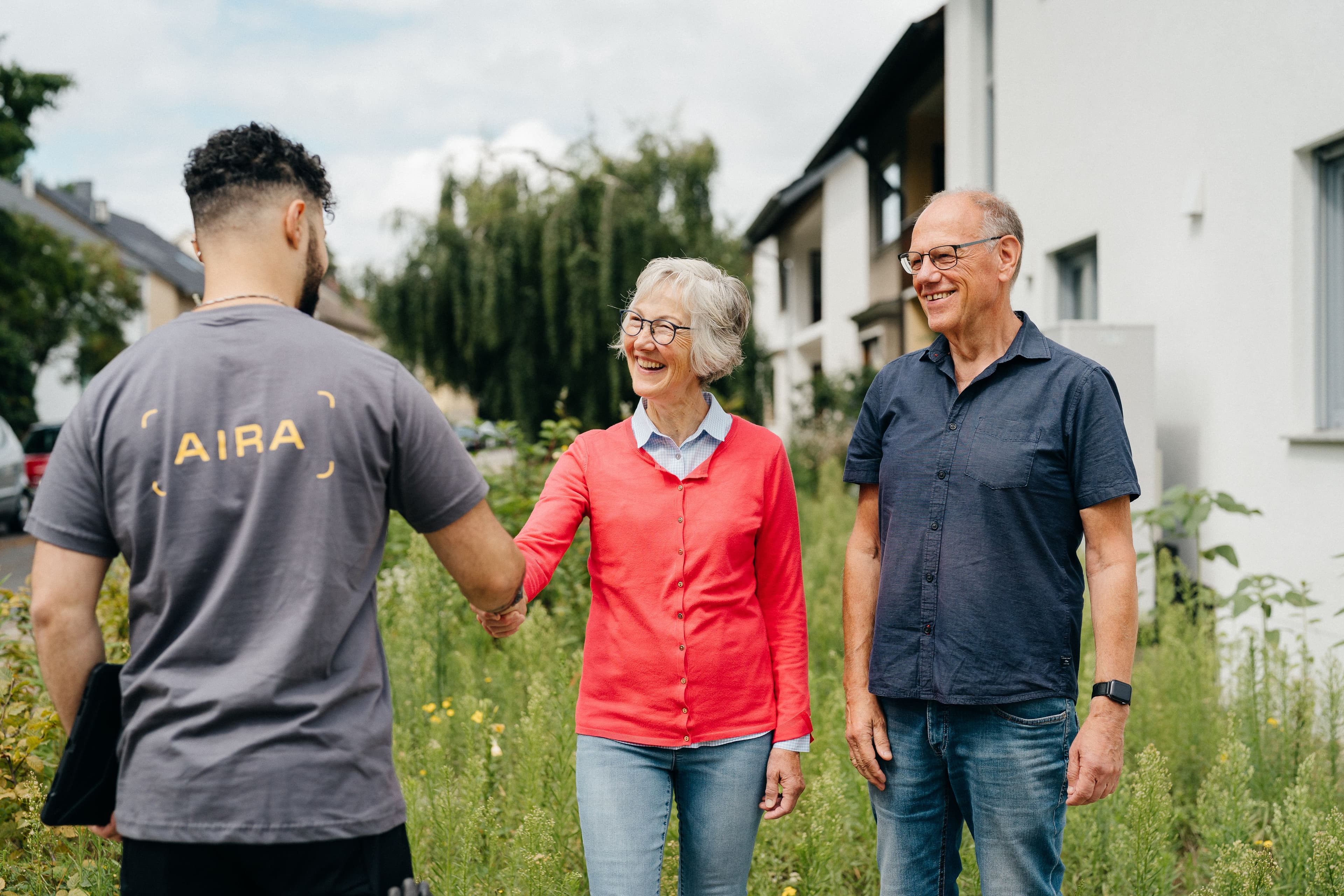 Ein Energie-Berater begrüßt ein älteres Ehepaar vor ihrem Haus
