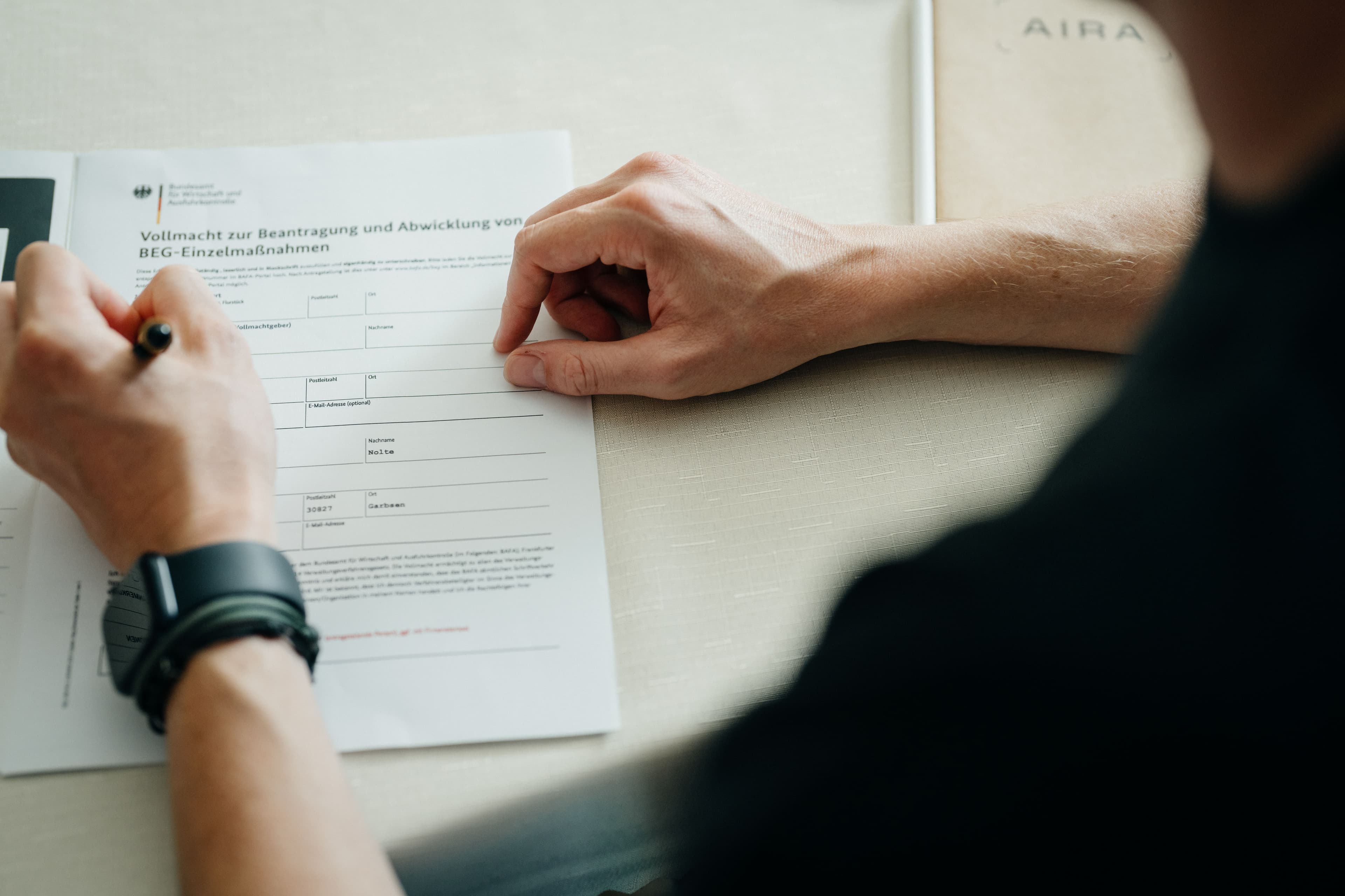 Person sitzt vor einer Informationsbroschüre und hält einen Stift in der Hand