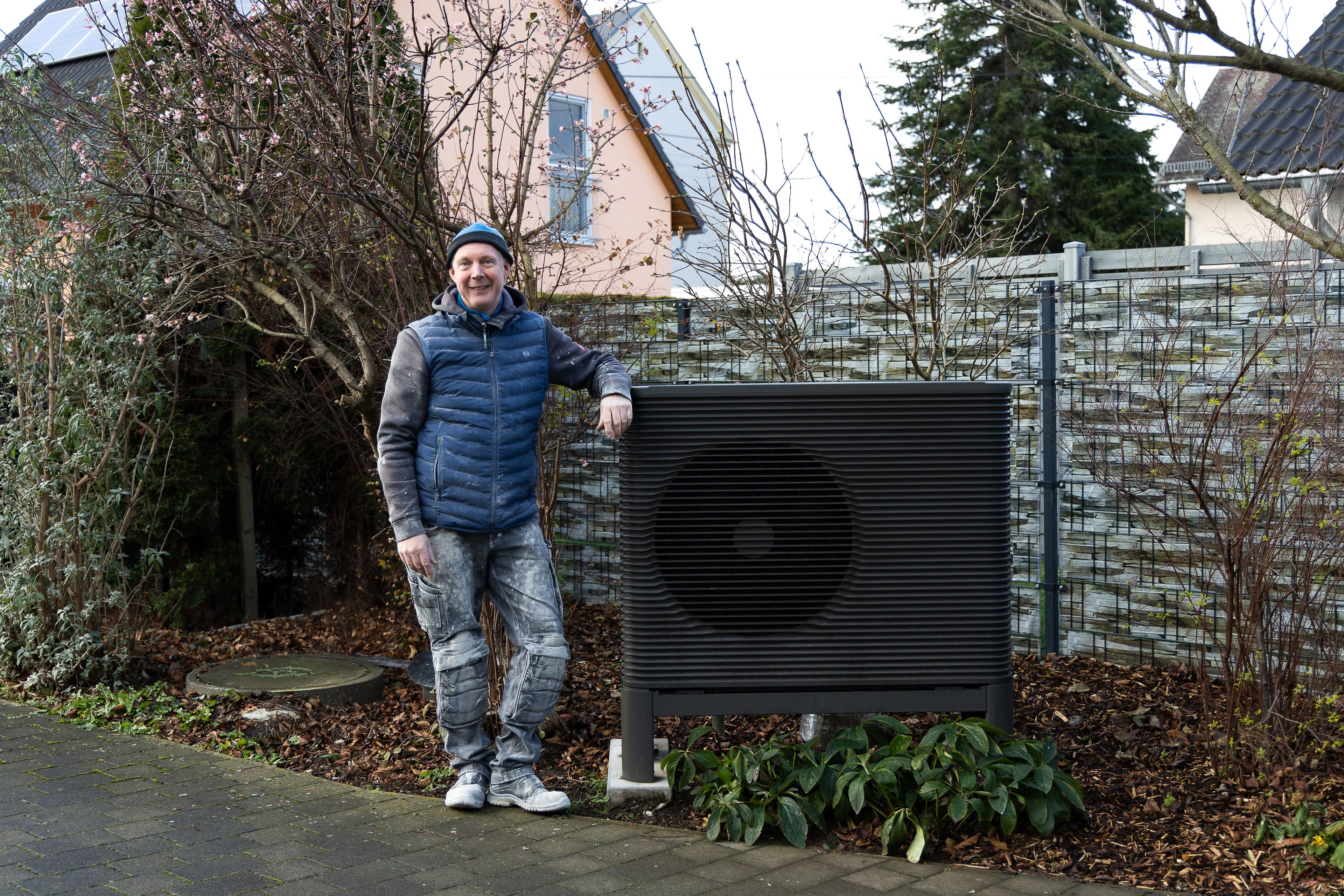 Kunde steht lächelnd neben seiner Wärmepumpe
