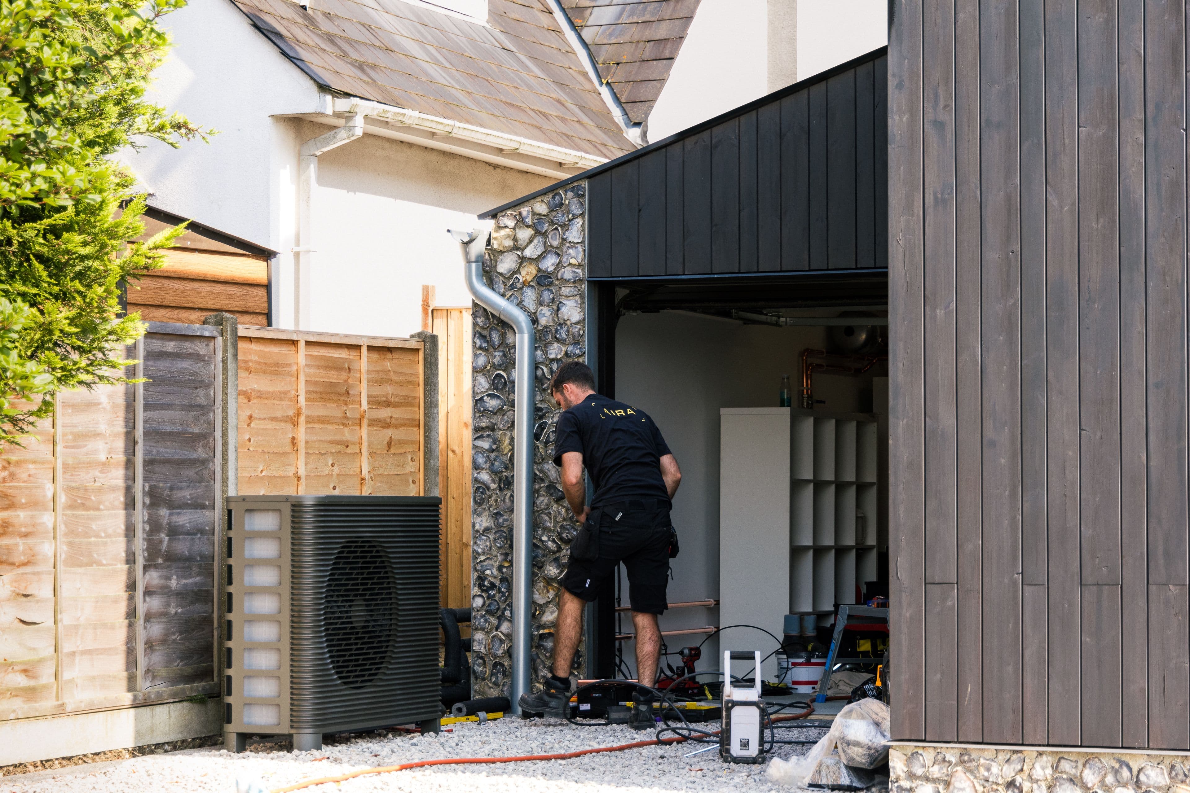 Aira technician installing an Aira air to water heat pump next to a fence