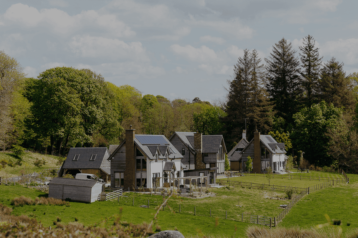 Picture of a house in the countryside with solar panels and Aira Heat Pump
