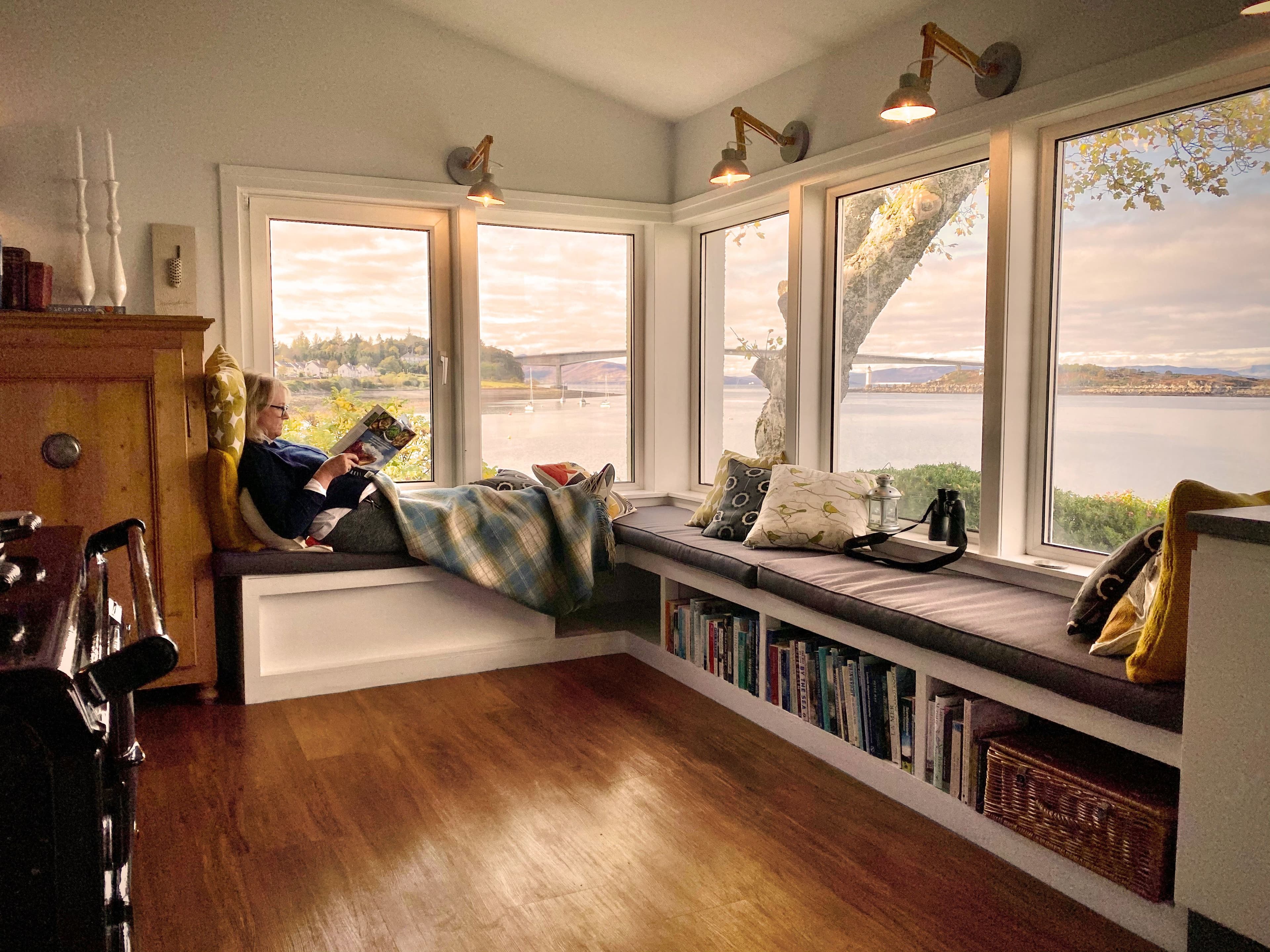 Woman sitting at her window in her home in Scotland reading a magazine 