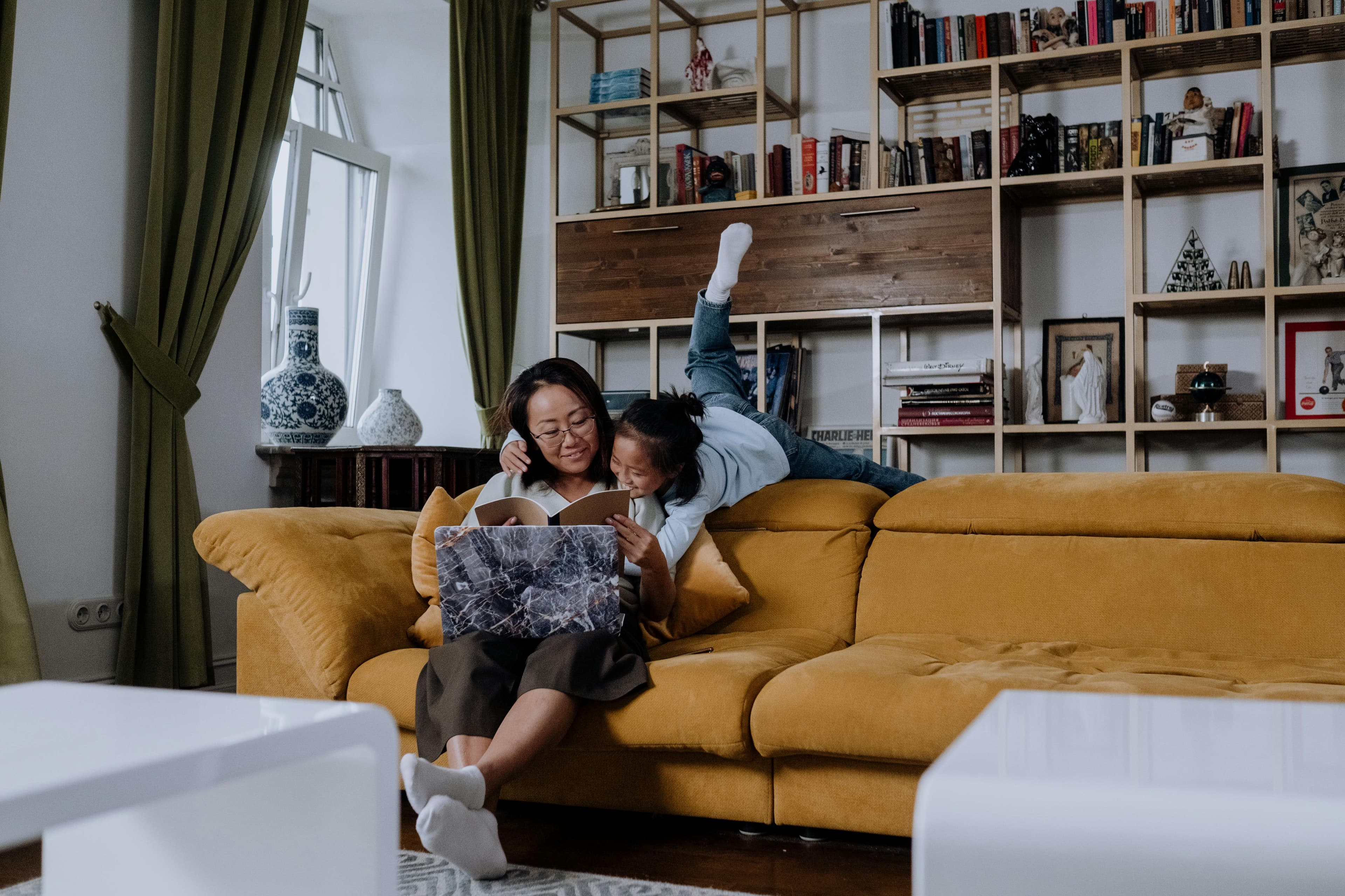 A mum and her child reading a book on a sofa in their living room