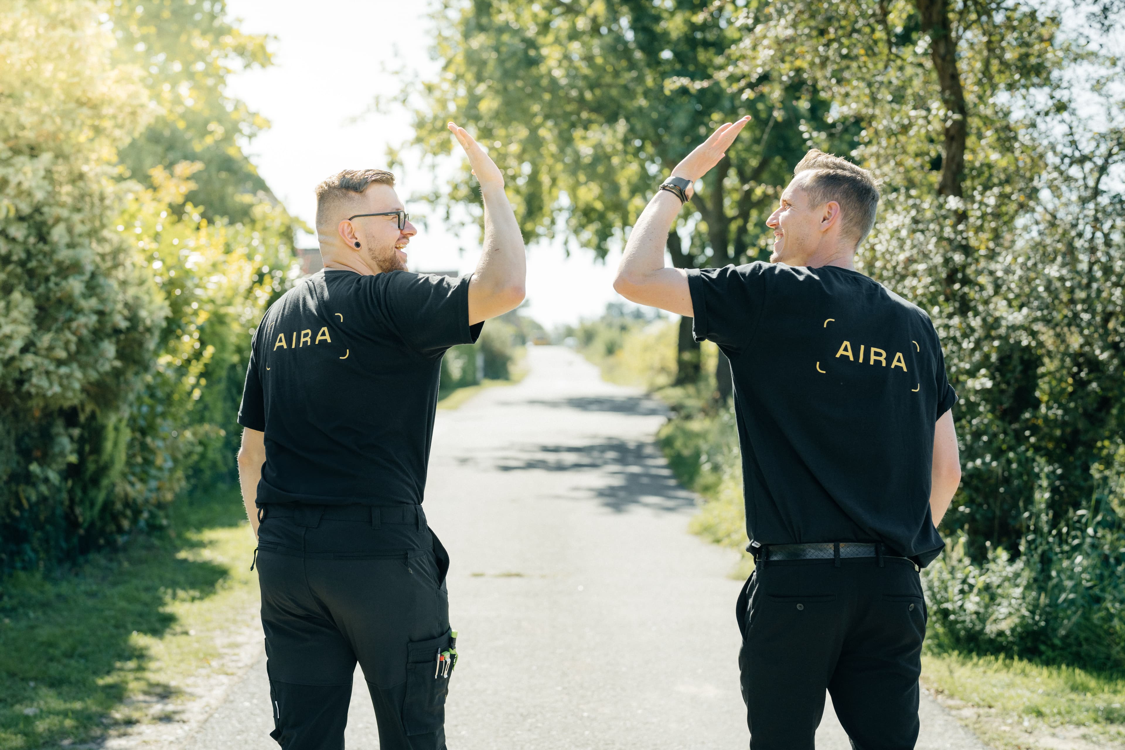 2 Energie-Experten von Aira laufen auf einer Straße in grünen Umgebung