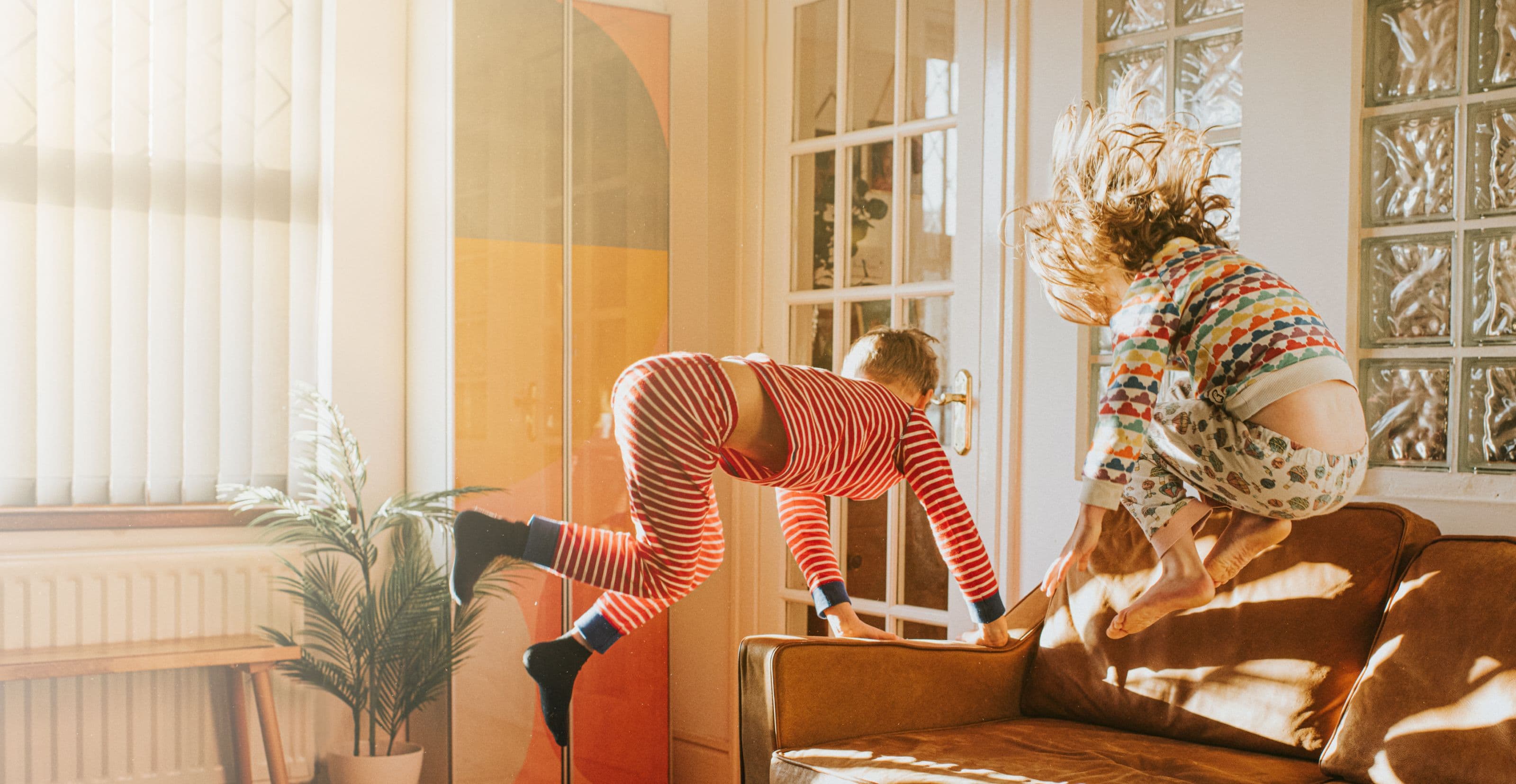 Children in pyjamas playing on a sofa