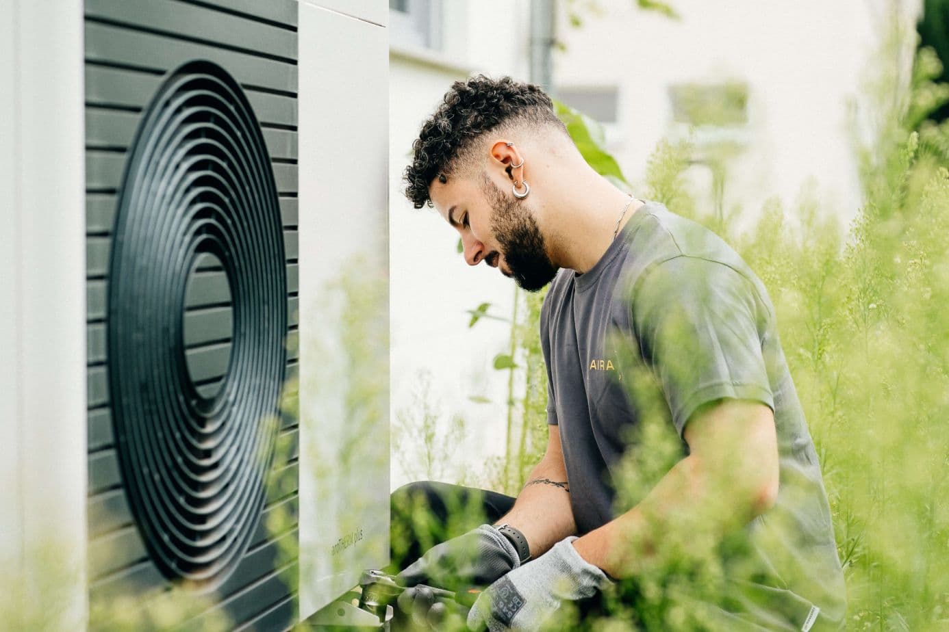 Aira employee bending down beside an air source heat pump