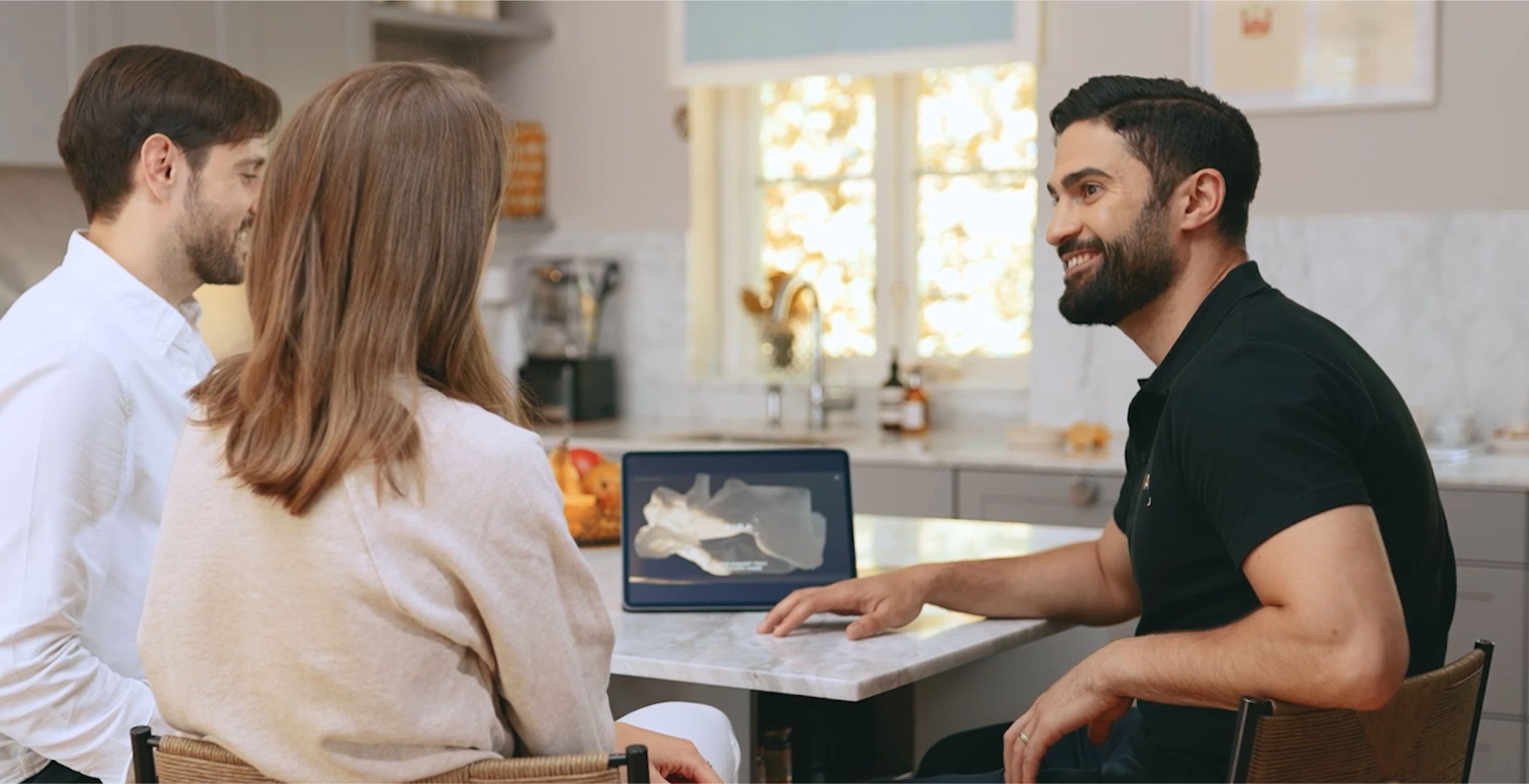 Aira employee sat with two customers in a kitchen with a tablet