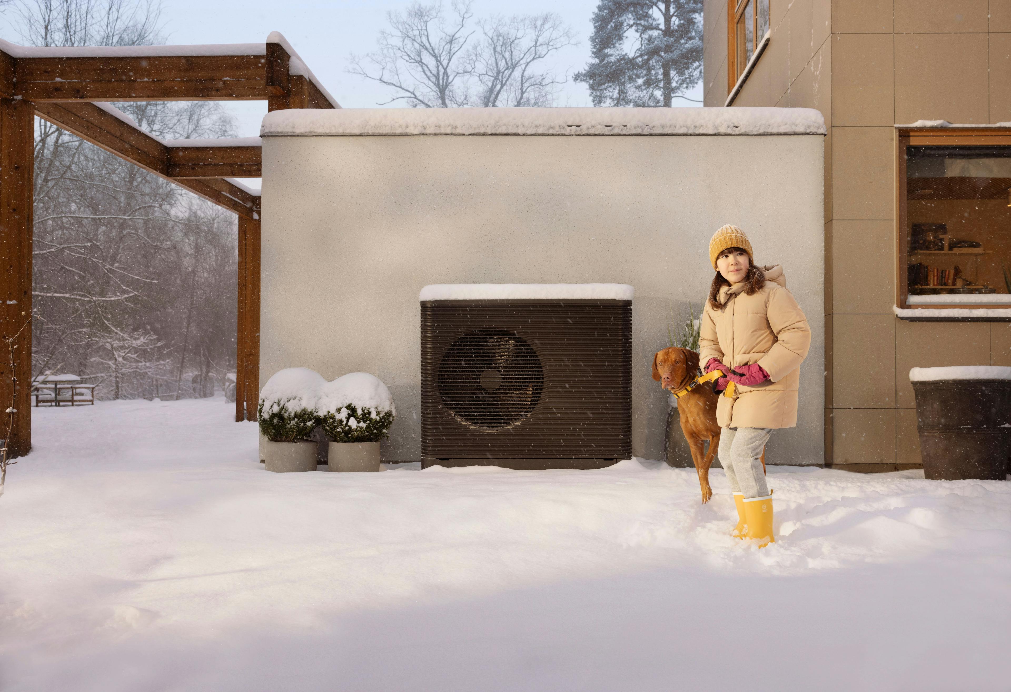 Girl and dog outside with heat pump in snow