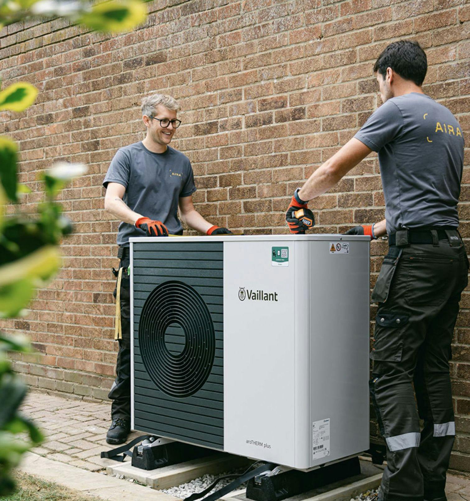 Zwei Techniker montieren eine Vaillant-Wärmepumpe bei einem Kunden am Haus