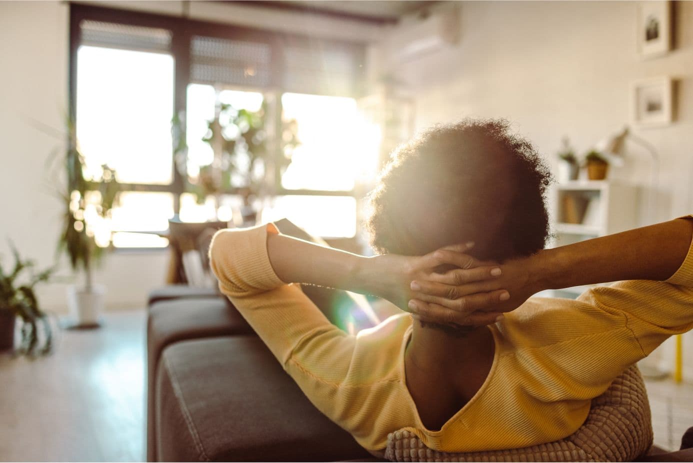 Behind a person sat on a sofa with their hands clasped behind their head